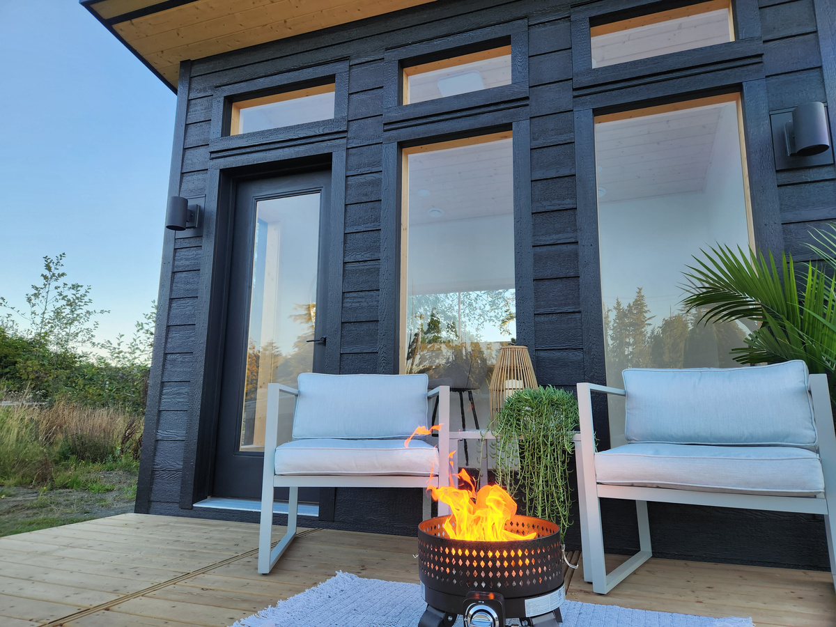 A modern prefab cabin with a firepit on a wood deck